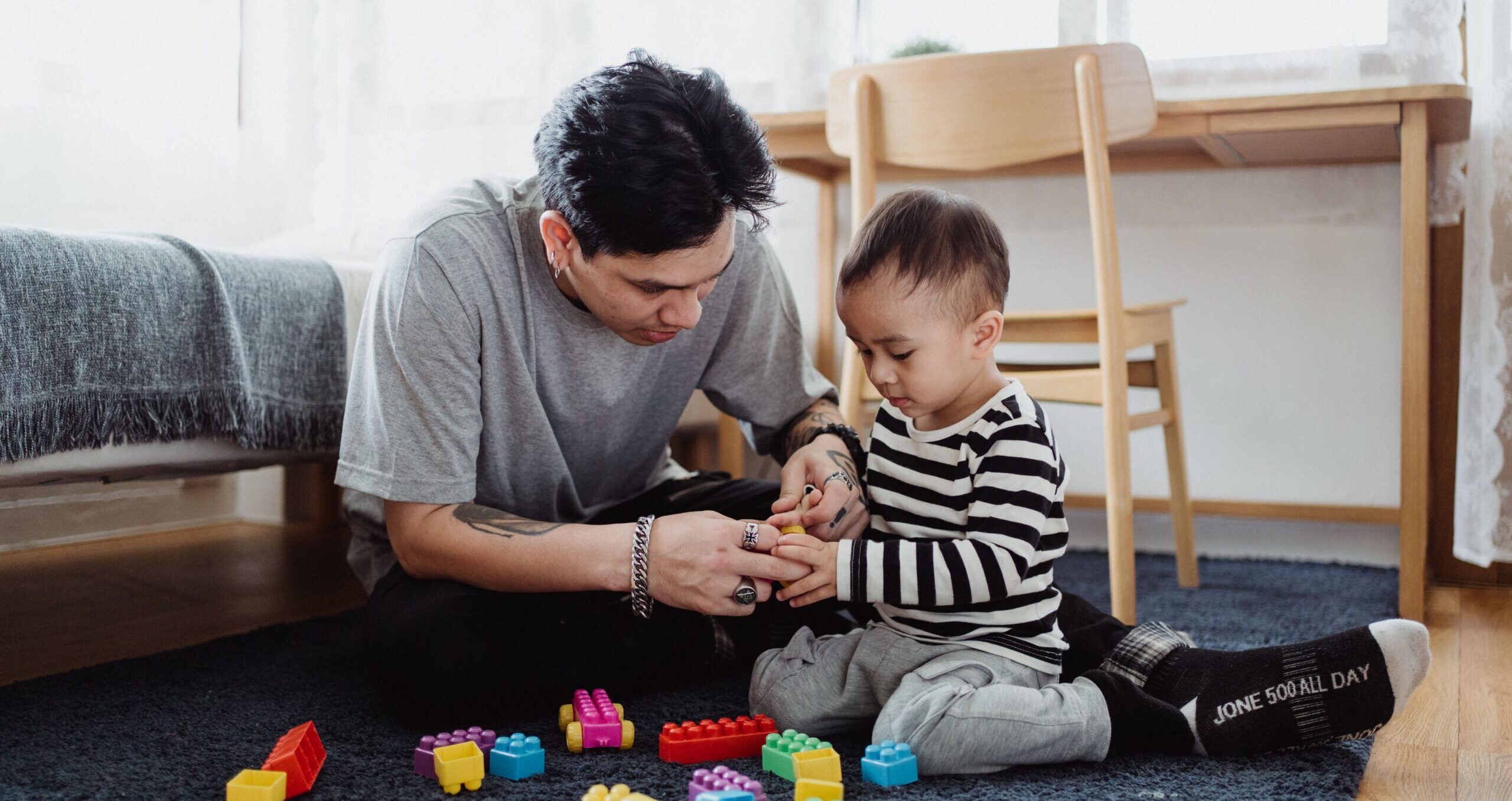 Father and son bond playing with colorful blocks in a cozy home setting.